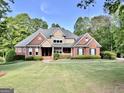 Attractive two-story brick home featuring a well-manicured lawn and lush landscaping at 6680 Bentley Trl, Cumming, GA 30040