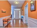 Inviting foyer with warm orange walls, hardwood floors, and white trim, leading to other rooms of the home at 702 Brambling Way, Stockbridge, GA 30281