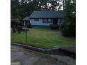 Quaint home featuring a lush front lawn and mature shrubs adding privacy at 402 Emmett St, Riverdale, GA 30274