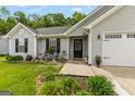 Close-up of home's front entrance featuring decorative landscaping, dark shutters, and inviting welcome sign at 12 Connie Trl, Grantville, GA 30220