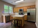 An open kitchen with stainless steel appliances, hardwood floors, a kitchen island, and natural light at 616 Wallnut Hall Tl, Woodstock, GA 30189