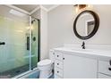 Bathroom featuring a glass-enclosed shower, sleek white vanity, and decorative round mirror at 760 Swan Ln, Canton, GA 30115