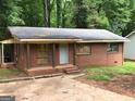 Shot of a single-story brick home with a flat roof and small front porch needing repair at 6186 Green Acres Sw Dr, Covington, GA 30014