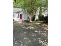 Charming home with a red front door, white siding and a driveway surrounded by mature trees at 1047 Plantation Nw Way, Kennesaw, GA 30144