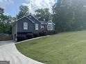 Side view of well-manicured lawn of gray home with a long driveway leading up to attached garage at 30 Wellington Trl, Covington, GA 30016