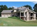 Back of brick home showing garage and screened in patios with large yard and a forest background at 315 Westbourne Dr, Tyrone, GA 30290