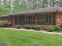 Ranch style home featuring a covered front porch with stone supports, and front yard landscaping at 205 Aberdeen Dr, Peachtree City, GA 30269