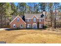 Charming two-story brick home boasts a symmetrical facade, complemented by lush greenery and a well-manicured front lawn at 212 Birkhill, Peachtree City, GA 30269