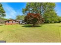 Scenic view of a brick house with a vast lawn and mature trees under a clear blue sky at 270 Lake Cir, Fayetteville, GA 30215