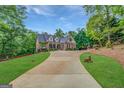 Expansive brick home with a long driveway nestled among mature trees and a green lawn at 95 Weslyan Way, Oxford, GA 30054