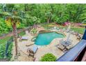 Tranquil backyard pool area surrounded by lush landscaping, a waterfall feature, and lounge seating at 95 Weslyan Way, Oxford, GA 30054