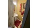 Small bathroom includes pedestal sink, mirror, wall decorations, and red rug at 1255 Chinon Pt, Lithonia, GA 30058
