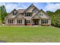 A well-manicured lawn in front of a light-brown two story house with dark trim and a red bench on the porch at 127 Grayson Myers Dr, Villa Rica, GA 30180