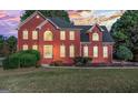 Beautiful two-story brick home with a lush green lawn and landscape under an amazing sunset sky at 176 Fairoaks Cir, Stockbridge, GA 30281