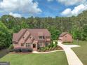 Beautiful brick home with a manicured lawn, mature trees, long driveway, and a guest house on a beautiful sunny day at 210 Short Rd, Sharpsburg, GA 30277