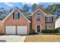 View of two-story brick home featuring an attached two-car garage and well-maintained landscaping at 6322 Shell Sw Dr, Atlanta, GA 30331