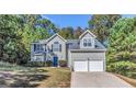 Charming home with a two-car garage, blue door and mature trees, providing a serene setting at 3130 Lower Creek Dr, Douglasville, GA 30135