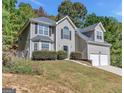 Traditional home featuring a two-car garage, manicured lawn, and mature trees at 3130 Lower Creek Dr, Douglasville, GA 30135