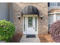 Close-up of a white front door with a black awning and sidelights, framed by brick and landscaping at 3941 Kings Pl, Ellenwood, GA 30294