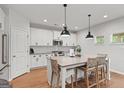 Modern white kitchen with a large island, pendant lighting, and stainless steel appliances at 152 Creekrise Pl, Palmetto, GA 30268