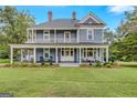 Charming two-story blue home featuring a large wrap-around porch and well-manicured lawn at 29 Indian Creek Rd, Locust Grove, GA 30248