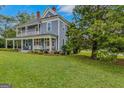 View of the home from the lawn, featuring a spacious yard and an inviting wrap-around porch at 29 Indian Creek Rd, Locust Grove, GA 30248