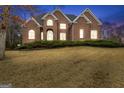 Charming two-story brick home at twilight with illuminated windows at 1442 Swiftwater Cir, Mcdonough, GA 30252