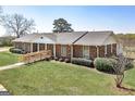 Spacious brick ranch with accessible ramp, complemented by lush green lawn and mature landscaping at 1092 E Lake Rd, Mcdonough, GA 30252