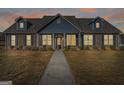 Charming single-story home featuring a brick facade, dormer windows, and well-maintained landscaping at dusk at 1141 Abundance Dr, Locust Grove, GA 30248