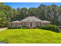 Charming brick home boasts a manicured lawn, lush greenery, and timeless architectural details at 127 Darwish Dr, Mcdonough, GA 30252