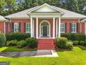 Inviting front porch with brick steps, white columns, and manicured shrubbery for a classic look at 127 Darwish Dr, Mcdonough, GA 30252