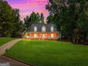 Beautiful brick home with a long covered porch, set against a colorful sunset sky and expansive front lawn at 1302 Eddie Craig Ct, Mcdonough, GA 30252