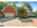 Brick home featuring an attached two-car garage and a covered front porch, nestled in a leafy, green landscape at 1302 Eddie Craig Ct, Mcdonough, GA 30252