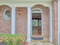 Covered doorway with brick wall and white pillars leading into entry with hard wood floors at 187 Eagles Club Dr, Stockbridge, GA 30281