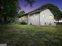 Side exterior of white brick home with a covered porch and manicured lawn at dusk at 701 Mask Rd, Brooks, GA 30205