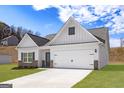 Beautiful home exterior featuring white siding, a two-car garage, landscaped front yard, and stone pillar details at 442 Prescott Way, Villa Rica, GA 30180