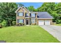Charming brick home with a well-manicured lawn, dark shutters, and an attached two-car garage, all bathed in sunlight at 242 Greenland Dr, Mcdonough, GA 30253
