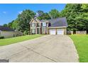 Two-story brick home featuring a two-car garage, ample driveway, and a beautifully maintained green lawn at 242 Greenland Dr, Mcdonough, GA 30253