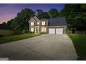 Charming two-story brick home with a well-manicured lawn, dark shutters and a three-car garage at dusk at 242 Greenland Dr, Mcdonough, GA 30253
