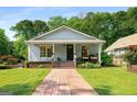 Inviting single-story home with a cozy front porch, beautiful landscaping, and a brick walkway at 1928 Main Nw St, Atlanta, GA 30318