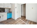 Bright kitchenette featuring sleek laminate flooring, white cabinetry, a blue dishwasher, and a side door entry at 2047 Charter Ln, Lithonia, GA 30058