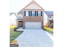 Two-story home featuring a brick facade, black shutters, a front yard, and a two-car garage at 2373 Aukerman Trce # 83, Hampton, GA 30228