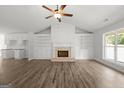 Light-filled living room featuring wood floors, fireplace, ceiling fan, and built-in bookshelves and cabinets at 3261 Broadnax Mill Rd # 2, Loganville, GA 30052