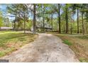 View of driveway approaching home with large trees surrounding the perimeter of the property at 130 Ashley Trace Dr, Locust Grove, GA 30248