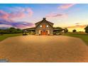 Stunning exterior view of barn with covered parking and large driveway with brick pavers at sunset at 290 Weldon Rd, Fayetteville, GA 30215