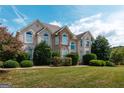 Charming two-story home with arched windows, a well-maintained lawn, and beautiful landscaping at 313 Masters Club Blvd, Hampton, GA 30228