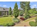 Beautifully landscaped green space in the community with walking paths and mature trees on a sunny day at 145 Kelmscott Ln, Fayetteville, GA 30214