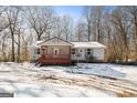 Inviting single-story home featuring a quaint front porch and lush trees in the winter at 5552 Smithfield Rd, Bowdon, GA 30108