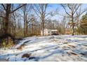 Expansive snowy yard with mature trees surrounding a cozy home with a porch at 5552 Smithfield Rd, Bowdon, GA 30108