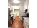 Galley kitchen with white cabinets, stainless steel appliances, and adjacent laundry area at 1448 Pine Log Ne Rd # C, Conyers, GA 30012